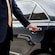 A professional driver in a suit opening the rear door of a luxury sedan